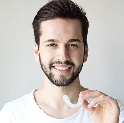 smiling man holding a set of clear aligners