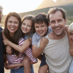 Multigenerational family with grandparents, parents, and 2 children smiling outside