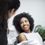 Photograph of a young Black female patient in a dental chair for a regular dental checkup.