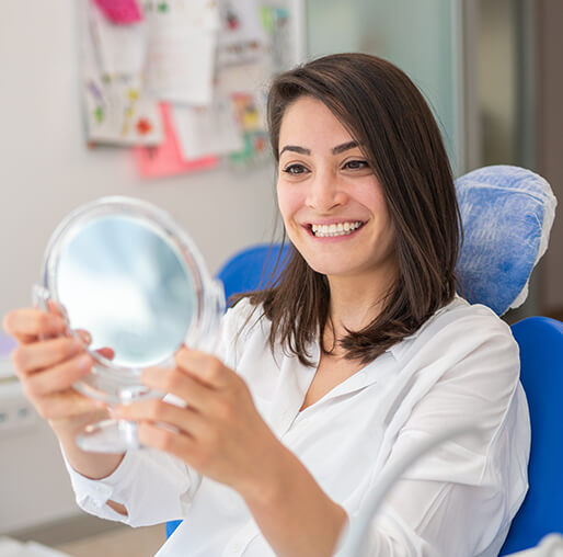 woman examining her smile in a mirror